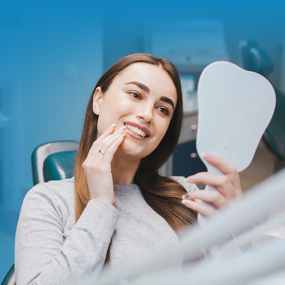 Woman smiling into handheld mirror